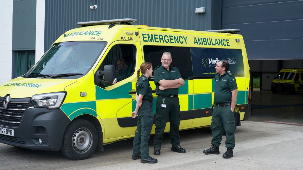 Ambulance staff chatting outside ambulance. They look friendly.