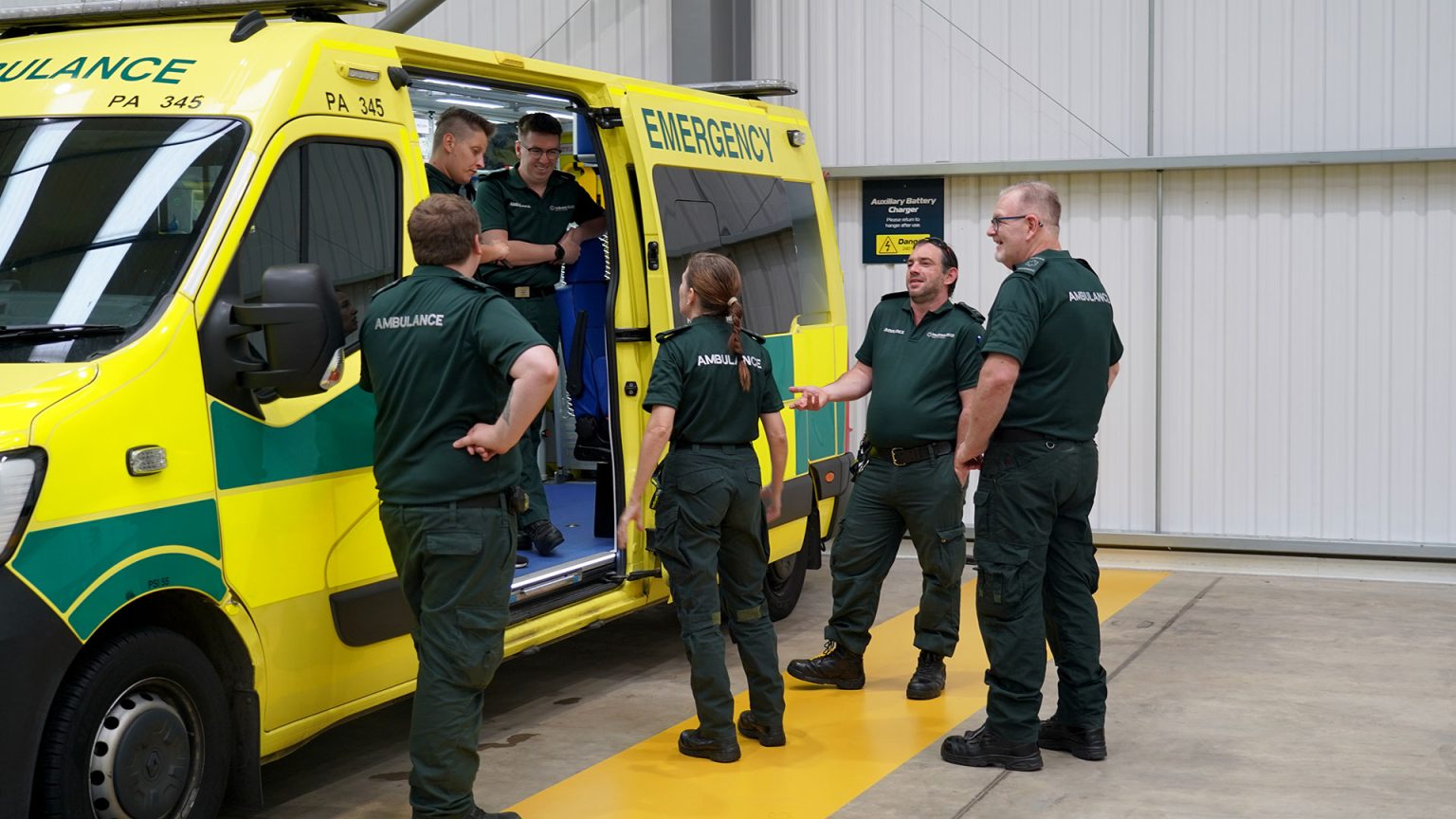 Paramedics discussing something outside of the side door of an ambulance