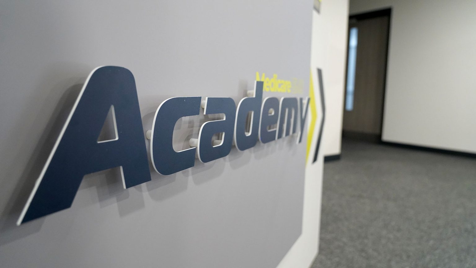 academy logo 3d angled on wall.